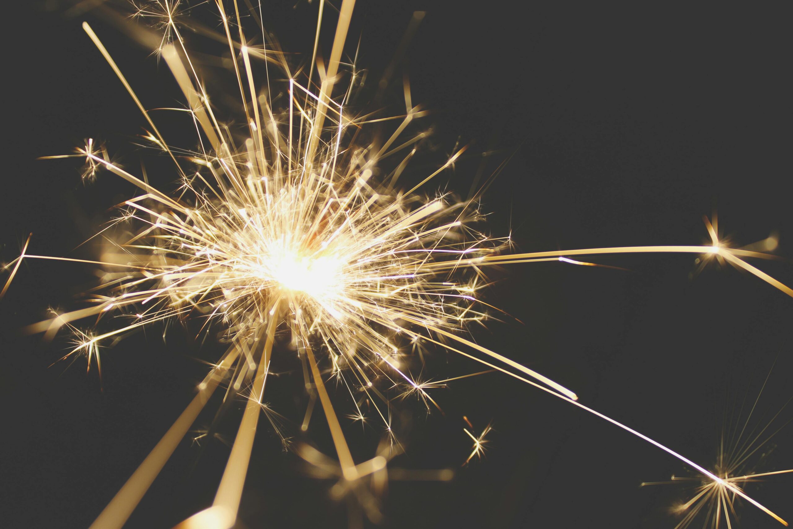 Close-up of a dazzling sparkler bursting with light against a dark background, perfect for celebrations.